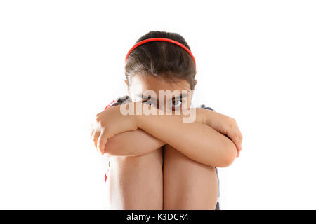 Une petite fille avec sa tête se cachant dans ses bras Banque D'Images