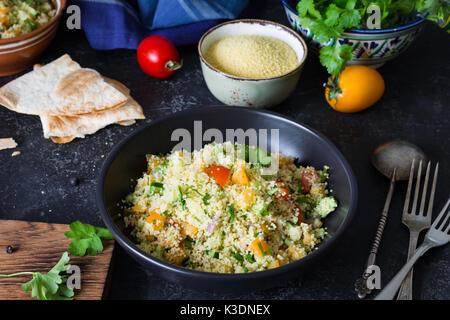 Cuisine arabe libanais : délicieux salade saine avec le couscous, les légumes frais et les verts appelés taboulé en noir bol. Une cuisine authentique Banque D'Images