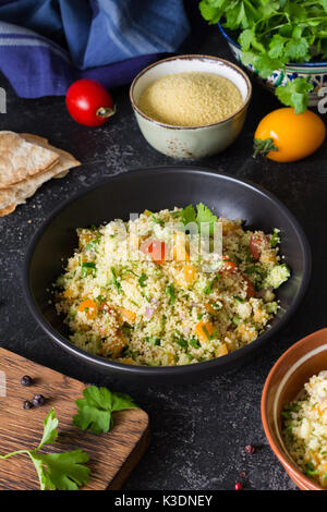 Cuisine arabe libanais : délicieux salade saine avec le couscous, les légumes frais et les verts appelés taboulé en noir bol. Une cuisine authentique Banque D'Images