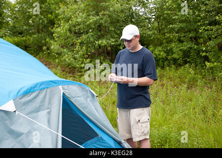 Un homme met en place son bleu tente dans la forêt pour le camping ou dormir à l'extérieur Banque D'Images