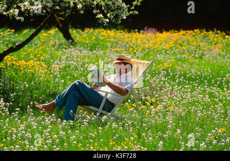 L'homme à la chaise longue dans le jardin Banque D'Images