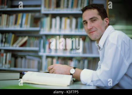 L'homme se lit dans une bibliothèque de livres Banque D'Images