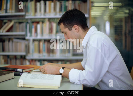 L'homme se lit dans une bibliothèque de livres Banque D'Images