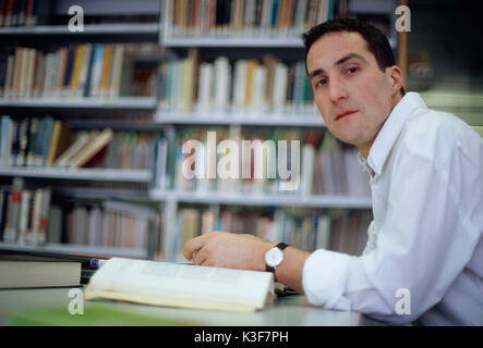 L'homme se lit dans une bibliothèque de livres Banque D'Images