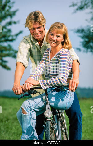 Jeune couple en vélo, femme assise sur stick Banque D'Images