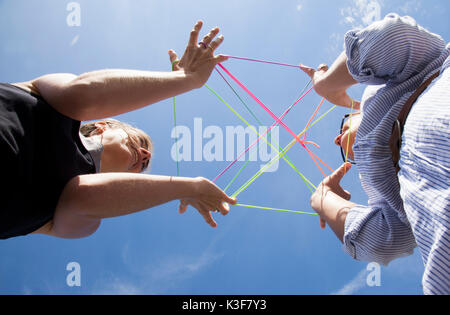 Low Angle View of Two Women Playing Game avec bandes élastiques colorés Banque D'Images