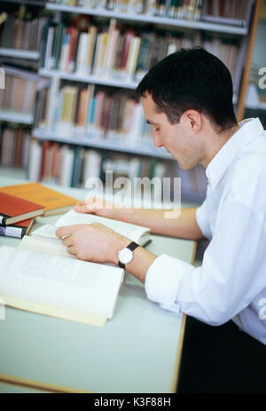 L'homme se lit dans une bibliothèque de livres Banque D'Images