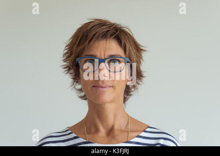 Taille portrait de femme adulte avec poils rouges, yeux bleus verts, lunettes et joyeuse expression du visage, en fond neutre. Doux naturel tous les jours Banque D'Images