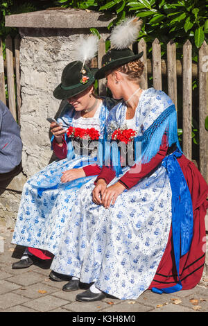 Germany, Bavaria, Munich, festival bavarois, les filles en costume traditionnel Looking at Smartphone Banque D'Images