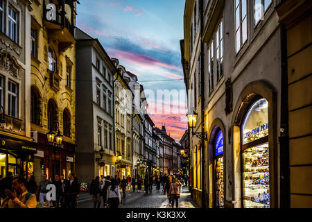 Une rue touristique dans la vieille ville de Prague au coucher du soleil avec les feux rougeoyant et une boutique ciel coloré dans la distance Banque D'Images