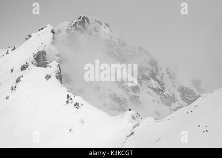 Un petit groupe de chamois sur le droit ci-dessous sur la photo contre la taille et inhospitableness par mauvais temps en hiver dans une montagne de l'Schöttelkarspitze dans le Soierngruppe dans le Karwendel. Banque D'Images
