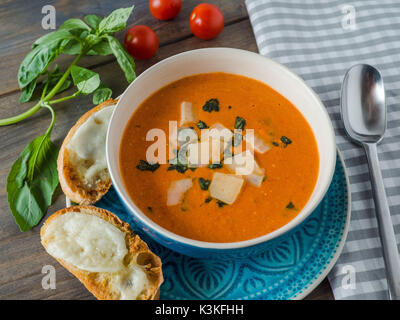 Soupe de tomates fraîches avec du fromage au four sur Ciabatta une table en bois, vue du dessus Banque D'Images