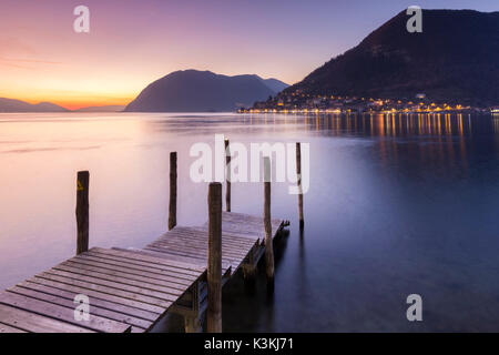 Une jetée dans Iseo, en face de Montisola Peschiera Maraglio et lors d'un coucher de soleil d'hiver de la ville, province de Brescia, Lombardie, lac d'Iseo, Italie. Banque D'Images