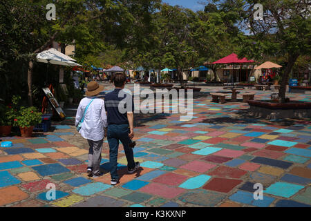 Couple marche main dans la main à travers les pavés peintes de couleurs vives de la Spanish Village Art Center Plaza dans Balboa Park, San Diego, CA en août 2017. Banque D'Images