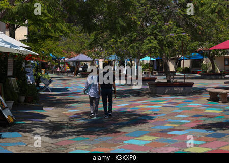 Couple marche main dans la main à travers les pavés peintes de couleurs vives de la Spanish Village Art Center Plaza dans Balboa Park, San Diego, CA en août 2017. Banque D'Images