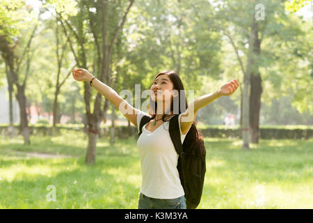 Happy girl avec ses bras ouverts, faisant face au soleil. La lumière du soleil brillait dans les bois. Banque D'Images