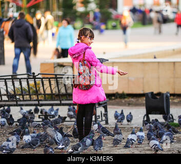 Irkoutsk, Russie - Oct 9,2015:une fille russe nourrir les pigeons à place de la ville d'Irkoutsk. Banque D'Images