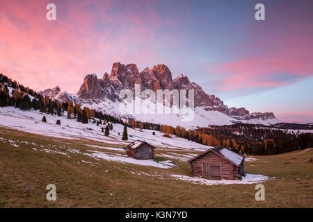 Lever du Soleil avec deux pavillons en bois et Odle Dolomites. Malga Gampen, Funes, Bolzano, Trentin-Haut-Adige - Sudtirol, Italie, Europe. Banque D'Images