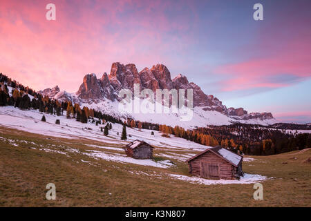 Lever du Soleil avec deux pavillons en bois et Odle Dolomites. Malga Gampen, Funes, Bolzano, Trentin-Haut-Adige - Sudtirol, Italie, Europe. Banque D'Images