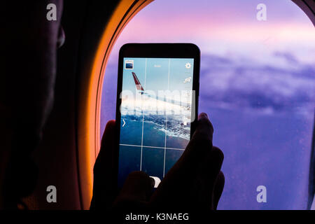 La Norvège, les îles Lofoten, Silhouette d'un homme à faire des photos de montagne et l'extension à l'aide d'un smartphone à partir d'un avion volant trought la fenêtre Banque D'Images