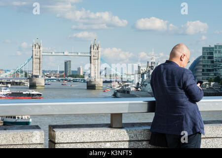 Un homme d'affaires chinois sur le pont de Londres en prenant une photo de Tower Bridge. Banque D'Images