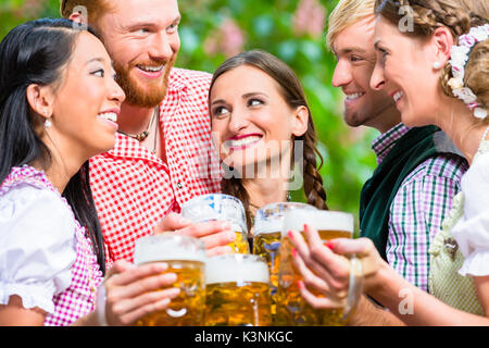 Les amis de s'amuser dans le jardin de la bière alors que clinking glasses Banque D'Images