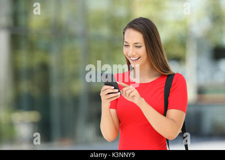 Entrepreneur unique portant une robe rouge à l'aide d'un téléphone mobile sur la rue Banque D'Images