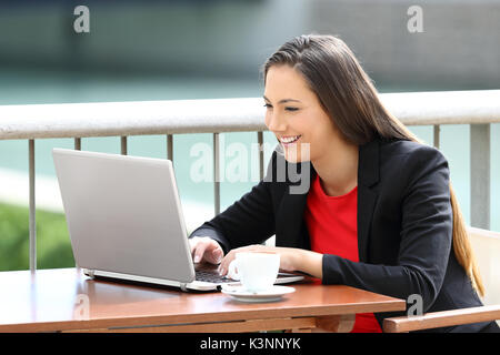 Heureux seule femme cadre entrant dans un ordinateur portable assis dans un bar Banque D'Images