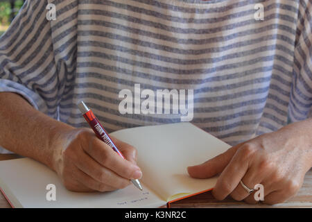 Femme écrit dans un journal de balle Banque D'Images