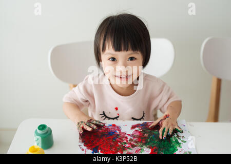 Little asian girl la peinture avec le pinceau et les peintures colorées Banque D'Images