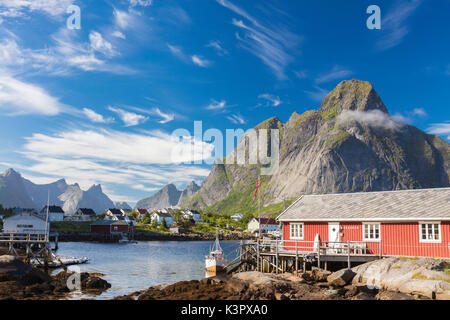 Maison typique de pêcheurs appelée Rorbu encadrée par des pics rocheux et d'une mer bleue Reine Lofoten, Norvège Europe Moskenes Banque D'Images