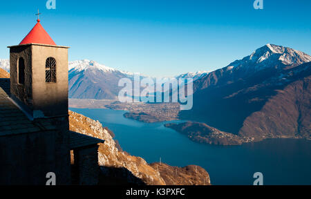 L'église de Saint Bernard et son clocher à Musso, le long de la Monti Lariani trail. Dans l'arrière-plan, le lac de Côme et Bassa Valteline avec le Mont Legnone à droite - Lombardie, Italie Europe Banque D'Images