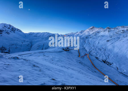 La lumière bleue du crépuscule sur le paysage enneigé et le col du Stelvio de virages en épingle de la vallée de la Valtellina Braulio Lombardie Italie Europe Banque D'Images