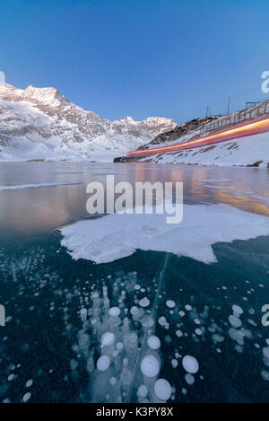 Le Bernina Express train passe à côté du lac gelé Bianco col de la Bernina canton des Grisons Engadine Suisse Europe Banque D'Images