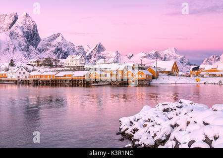 Les couleurs de l'aube les cadres de maisons de pêcheurs entouré de sommets enneigés Sakrisøy Reine Nordland îles Lofoten Norvège Europe Banque D'Images