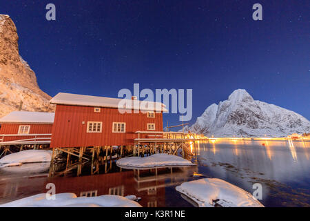 Nuit étoilée sur les pistes enneigées entouré par les maisons de pêcheurs de la mer congelés et Reinevagen Bay Iles Lofoten Norvège Europe Banque D'Images