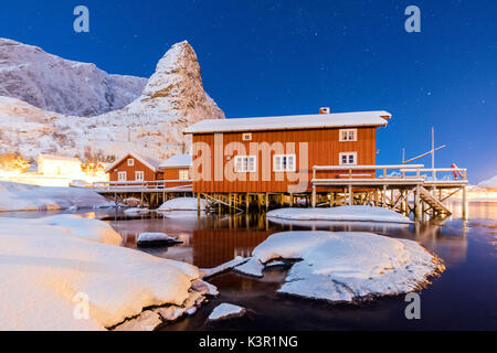 Nuit étoilée sur les pistes enneigées entouré par les maisons de pêcheurs de la mer congelés et Reinevagen Bay Iles Lofoten Norvège Europe Banque D'Images