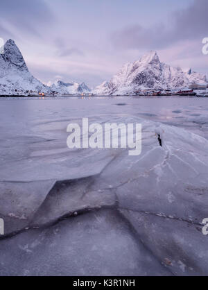 La mer gelée et les cimes enneigées du village de pêcheurs de trame au coucher du soleil Reine Nordland îles Lofoten Norvège Europe Banque D'Images