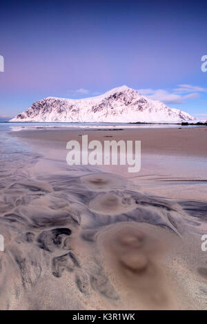 Ciel rose et des sommets enneigés encadrent la plage au coucher du soleil Skagsanden surréaliste Flakstad Nordland County Iles Lofoten Norvège Europe Banque D'Images