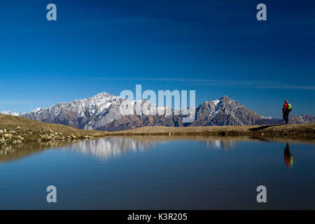 Un randonneur le long de la crête du mont San Primo reflétée dans un étang saisonnier. De là, la vue s'étend sur Grignetta et Grignone. Bellagio. Le lac de Côme. Lecco. La Lombardie. L'Italie. L'Europe Banque D'Images