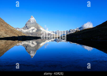 Randonneur admire le Cervin reflète dans le lac Stellisee Zermatt Canton du Valais Alpes Pennines Suisse Europe Banque D'Images