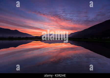 Réserve naturelle de Pian di Spagna inondé de sommets enneigés reflétée dans la mer au coucher du soleil la Valtellina Lombardie Italie Europe Banque D'Images