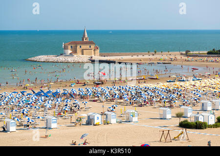 Parasols sur la plage de sable donnant sur le Sanctuaire de la Madonna dell'Angelo à Caorle Venise province Vénétie Italie Europe Banque D'Images