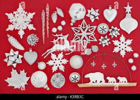 Symboles de Noël avec des décorations babiole en argent et blanc sur fond rouge. Banque D'Images