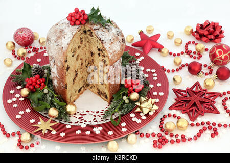 Panettone au chocolat gâteau de Noël avec des décorations babiole, chocolats emballés d'aluminium, de petits flocons, hiolly et verdure d'hiver on white glitter bac Banque D'Images