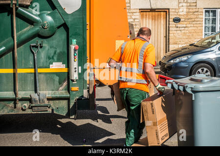 Un conseil ouvrier en tenant le carton déchets à la refuser camion sur une journée ensoleillée. Langtoft, près de Peterborough. Lincolnshire, Angleterre, Royaume-Uni. Banque D'Images