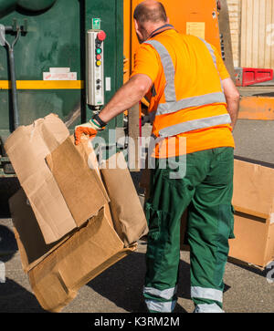 Un conseil ouvrier en tenant le carton déchets à la refuser camion sur une journée ensoleillée. Langtoft, près de Peterborough. Lincolnshire, Angleterre, Royaume-Uni. Banque D'Images
