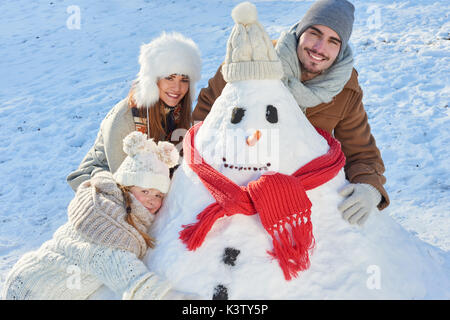 Famille heureuse en hiver bonhomme de bâtiment dans le parc Banque D'Images