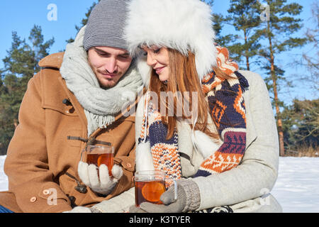 Couple heureux de boire du thé dans le parc sur leurs vacances d'hiver Banque D'Images