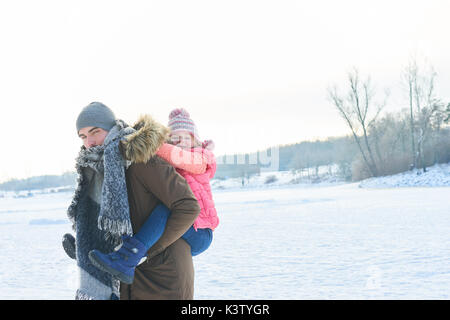 Père donne fille piggyback ride en hiver et s'amuser dans la nature snowey Banque D'Images